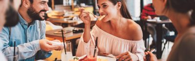 A woman eating food with a fork while her friends talk to her