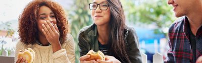 Three friends eating a sandwich and smiling