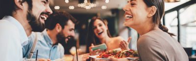 Friends smiling and chatting together as they eat a meal