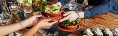 Two people passing food across a table